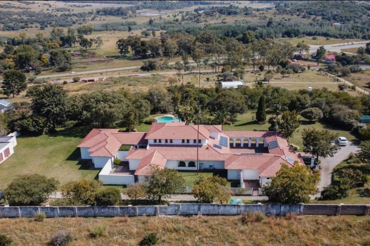 Aerial view of a large small holding property featuring a sprawling residence with a tiled roof, swimming pool, and extensive landscaped grounds.