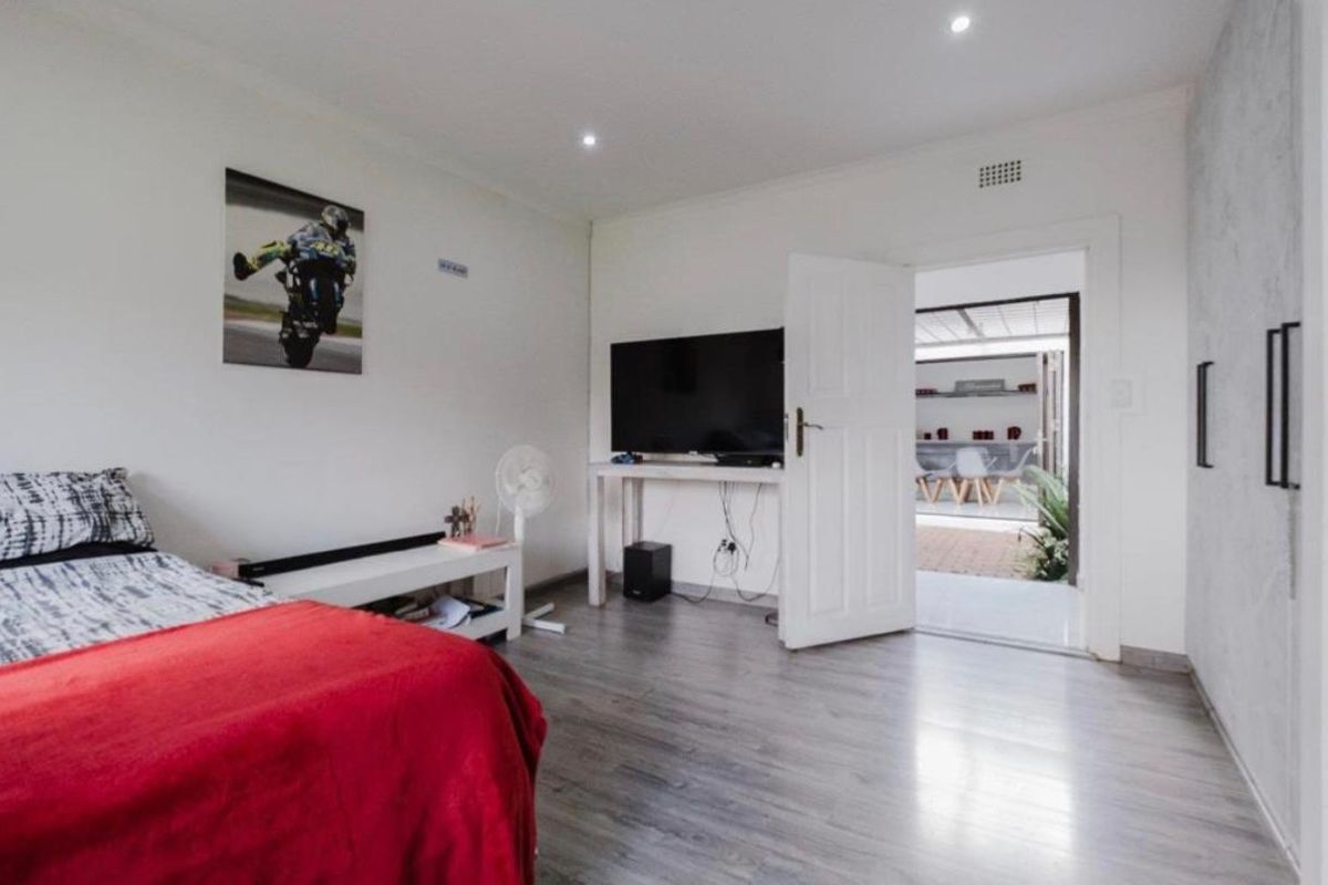 A bedroom featuring laminate flooring, recessed ceiling lighting, and direct access to an outdoor patio area.