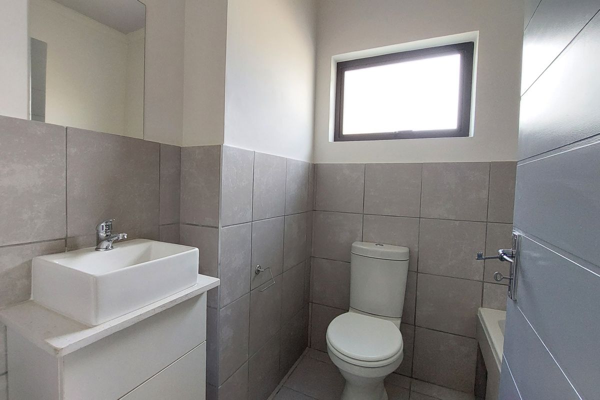 A clean, modern bathroom featuring a vessel sink vanity, tiled walls, and a toilet, finished with neutral tones and natural light.