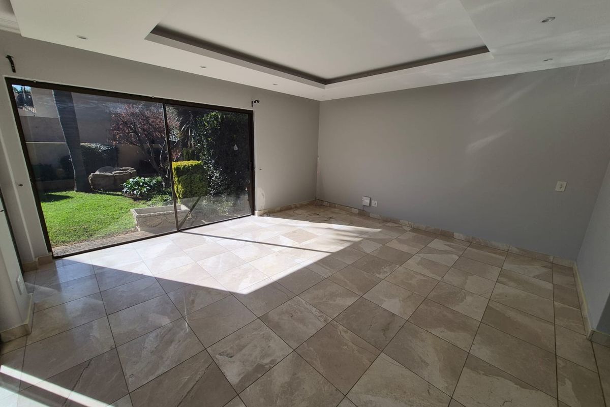Spacious living area featuring large sliding glass doors, neutral tiled flooring, and a modern recessed ceiling design with integrated lighting.