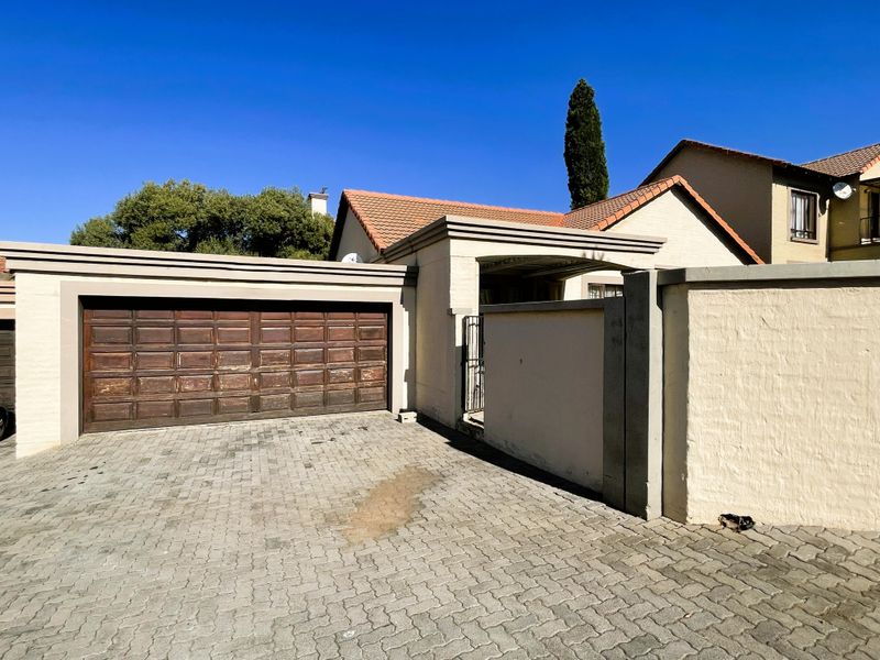 Front exterior view featuring a double garage with a paved driveway and secure perimeter walling.