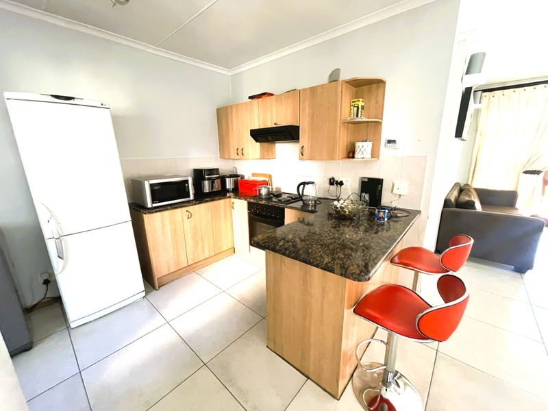 Open-plan kitchen featuring laminate cabinetry, granite countertops, a breakfast bar, and tiled flooring, seamlessly connected to the adjacent living area.