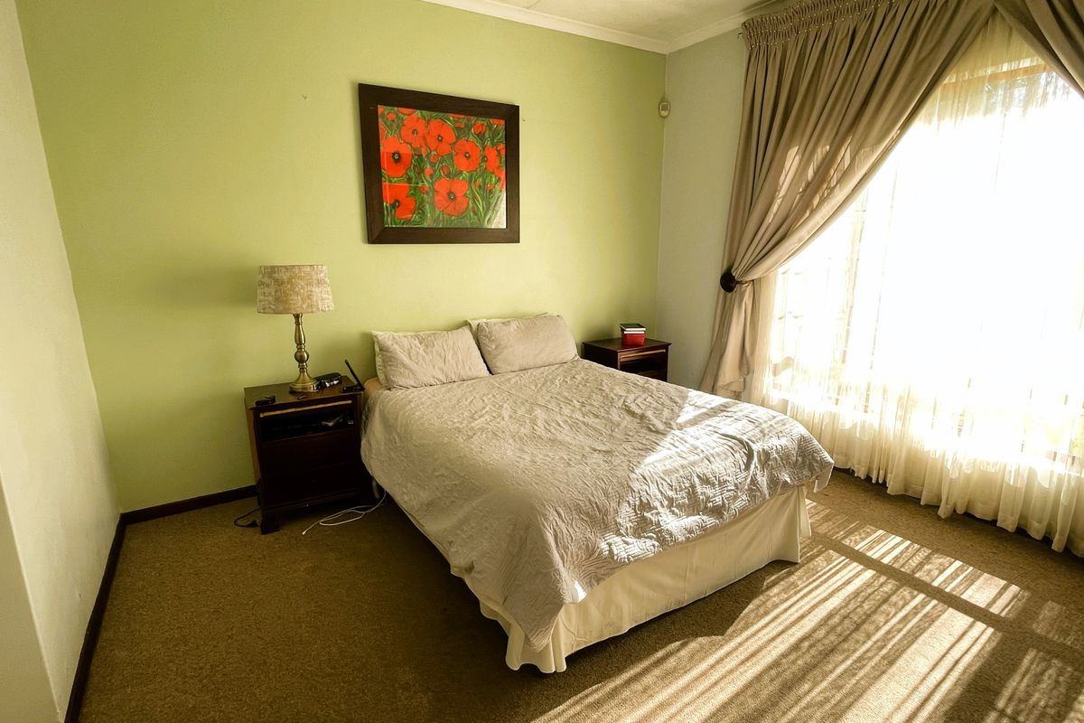 A bedroom featuring carpeted flooring and large windows with curtain rails, providing natural light.