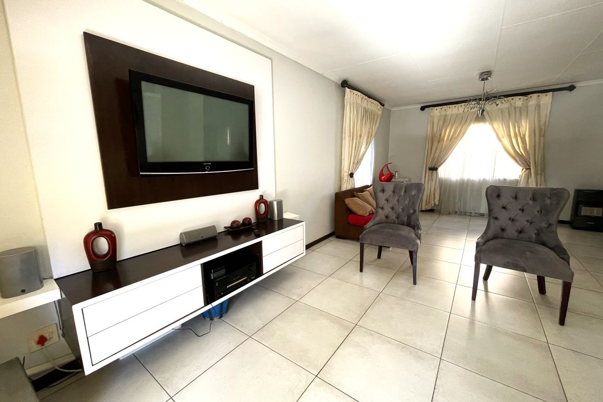 A living room featuring tiled flooring and a built-in media console unit, offering a functional space with natural light from the window.