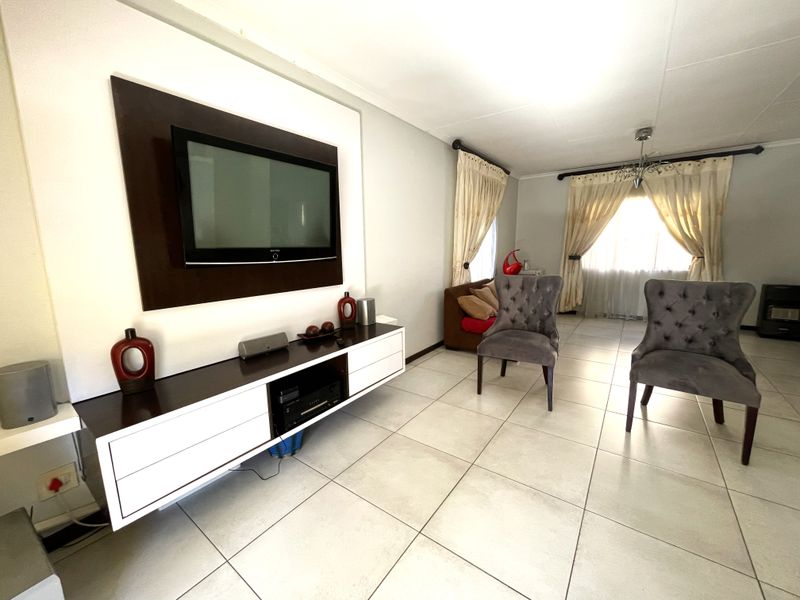 A living room featuring tiled flooring and a built-in media console unit, offering a functional space with natural light from the window.