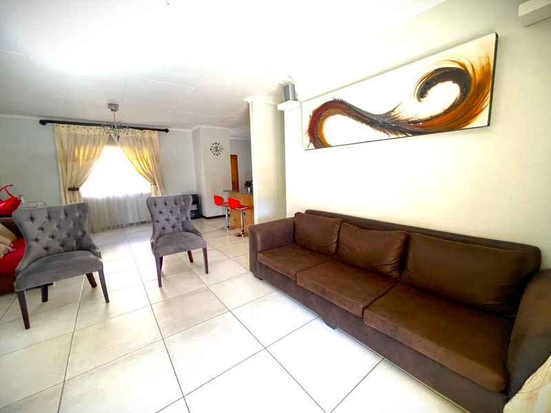Open plan living area featuring tiled flooring and a breakfast bar, connecting the lounge space to the kitchen area.