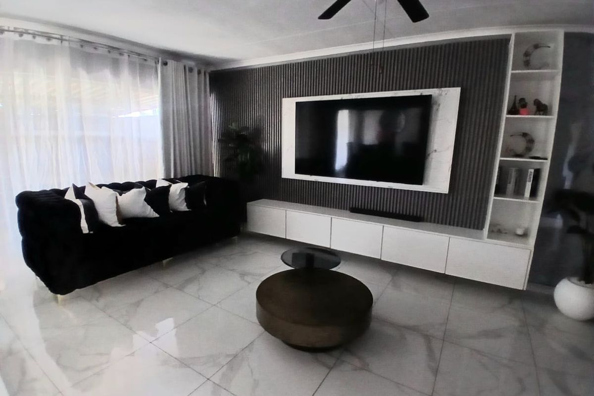 Modern living room featuring large format marble-look floor tiles, a custom built-in media wall with slatted paneling, and integrated shelving.