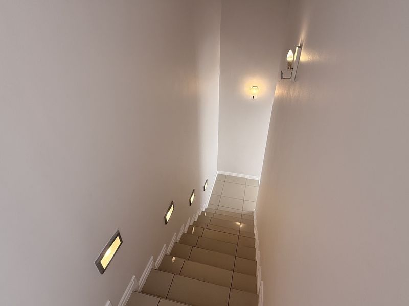 A clean, modern staircase featuring tiled steps and integrated recessed wall lighting for safety and ambiance.