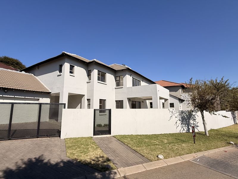 A well-maintained double-story residential property featuring a plastered facade, tiled roof, paved driveway, and secure boundary wall with gated access.