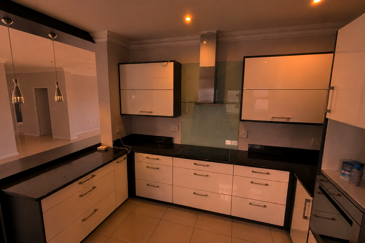 Modern kitchen featuring high-gloss cabinetry, granite countertops, integrated appliances, and a breakfast bar overlooking the open-plan living area.