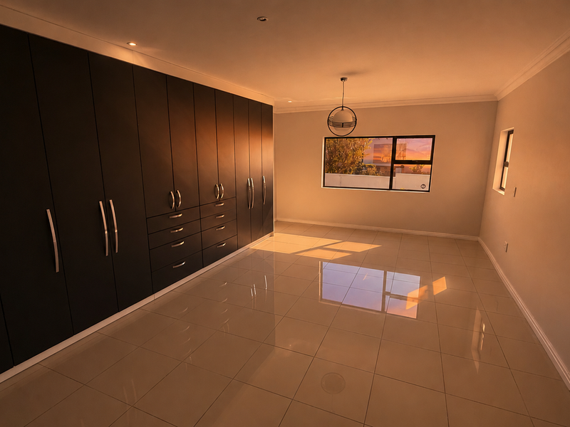 Spacious bedroom featuring extensive dark built-in cabinetry, polished tiled flooring, and large windows providing ample natural light.