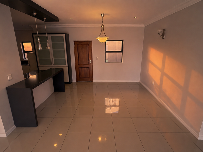 Spacious open-plan living and dining area featuring polished tiled flooring, modern pendant lighting, and a built-in breakfast bar with integrated cabinetry.