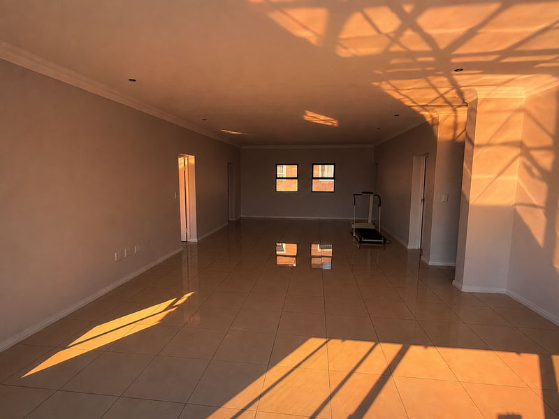 A spacious, sunlit open-plan living area featuring neutral tiled flooring, recessed lighting, and clean finishes, offering a versatile blank canvas for interior design.
