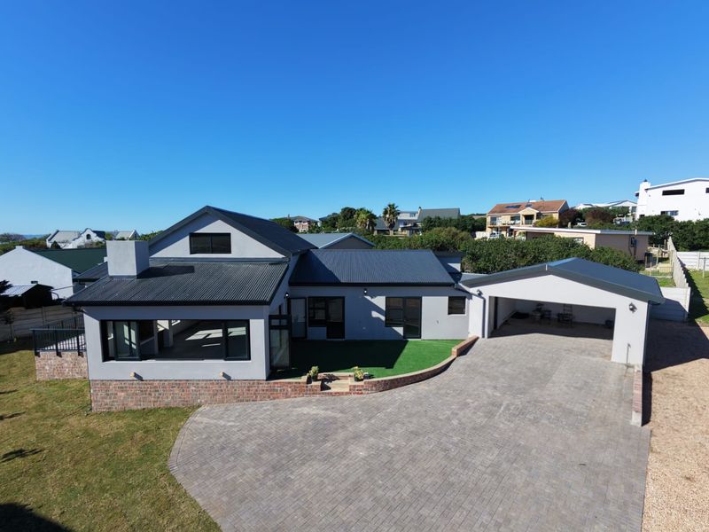 Aerial view of a modern single-story house featuring a paved driveway, double garage, and a covered patio area with a well-maintained exterior.