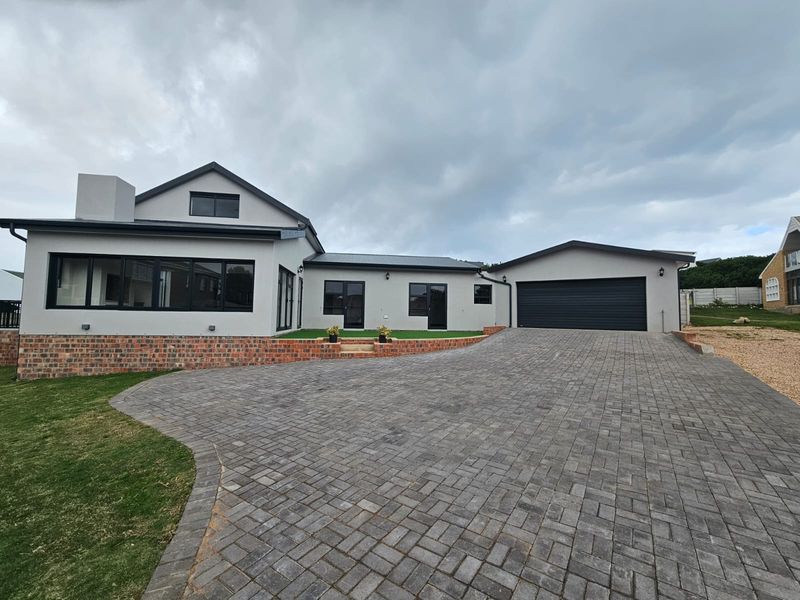Modern single-story house featuring a paved driveway, double garage, and a clean, contemporary exterior finish with contrasting black window frames.