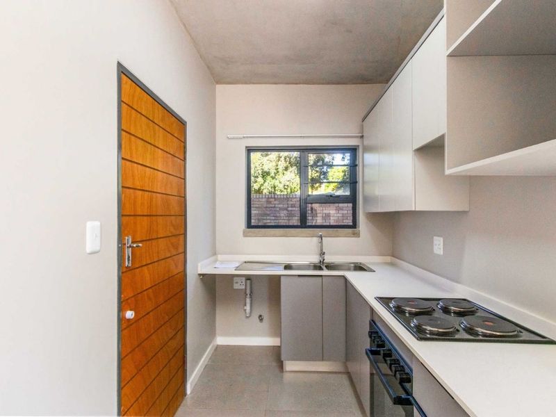 A clean, modern kitchen featuring built-in cabinetry, a stainless steel sink, and an integrated electric hob and oven, offering a functional and minimalist workspace.