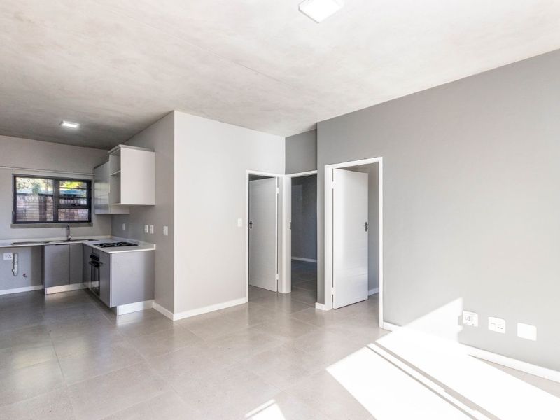 Modern open-plan living area featuring a sleek kitchen with built-in appliances and neutral tiled flooring throughout.