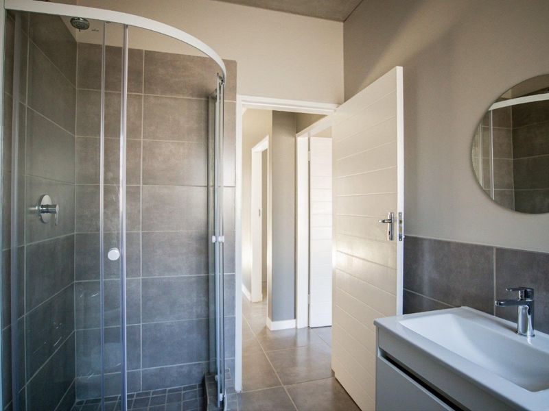 Modern bathroom featuring a glass shower enclosure, tiled walls, and a sleek vanity basin with contemporary fixtures.