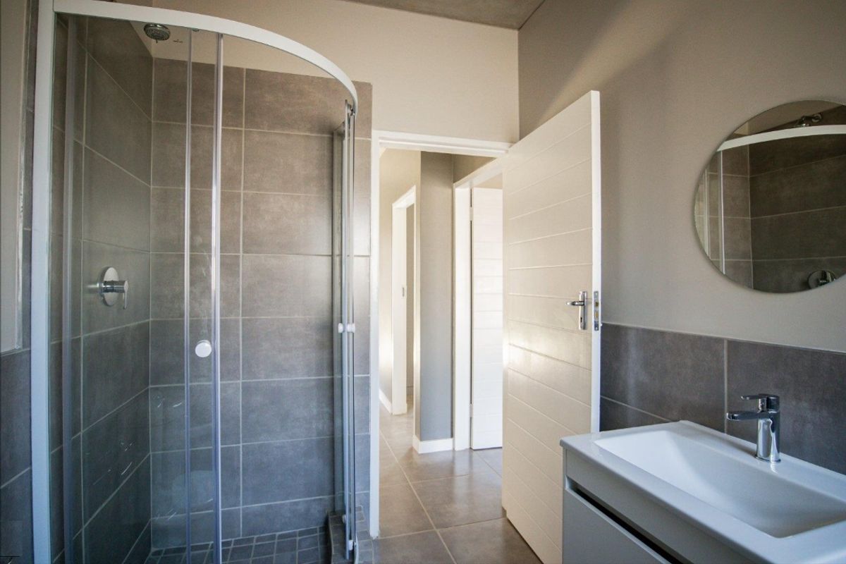 Modern bathroom featuring a glass shower enclosure, tiled walls, and a sleek vanity basin with contemporary fixtures.