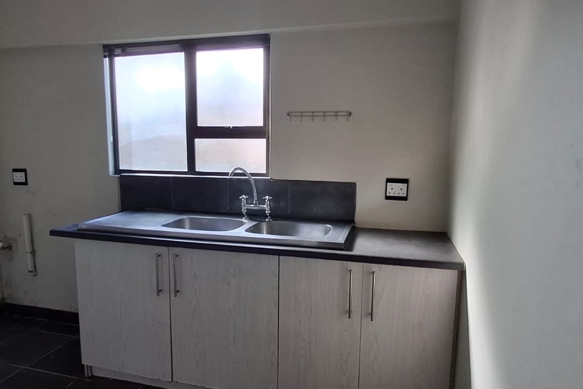 A functional kitchen area featuring built-in cabinetry, a double sink with a tiled splashback, and essential plumbing and electrical connections.