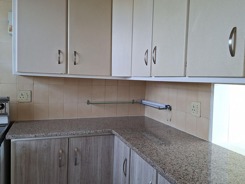 A functional kitchen featuring granite countertops, tiled backsplash, and a mix of upper and lower cabinetry with modern hardware.