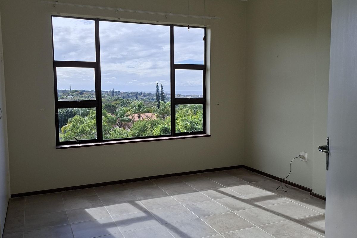 An empty bedroom featuring tiled flooring, a ceiling fan, and a large window offering scenic views.