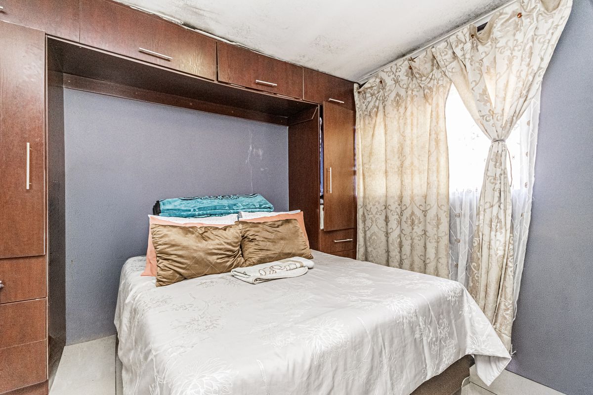 Bedroom featuring built-in cabinetry and overhead storage cupboards, showing signs of ceiling water damage and wear.
