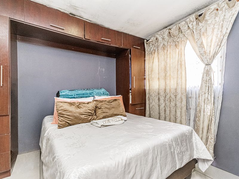 Bedroom featuring built-in cabinetry and overhead storage cupboards, showing signs of ceiling water damage and wear.