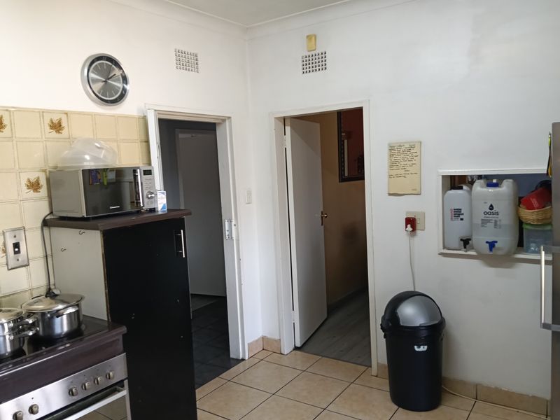 A functional kitchen area featuring built-in stove, tiled splashback, and recessed wall shelving, showing signs of wear and dated finishes.