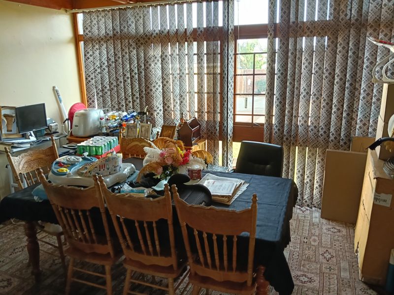 A dining room featuring large floor-to-ceiling windows with vertical blinds, providing ample natural light and access to the exterior.