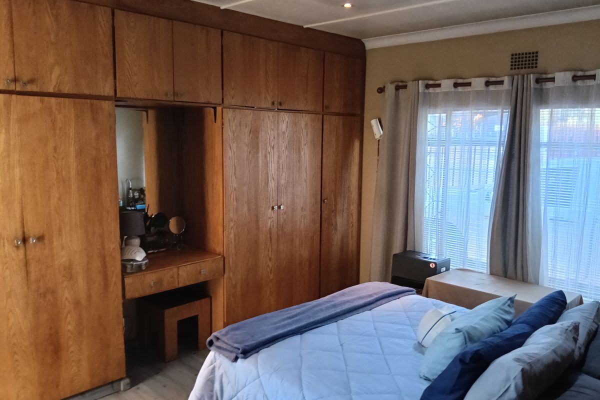 A bedroom featuring extensive floor-to-ceiling built-in wooden cabinetry with an integrated vanity unit and neutral wall finishes.