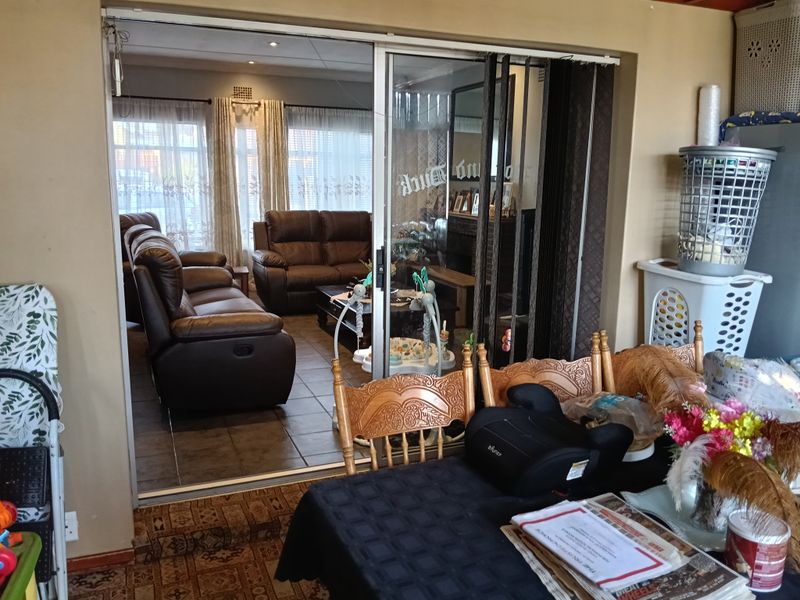 Open plan living area featuring tiled flooring and large sliding glass doors connecting the indoor space to the adjacent dining area.