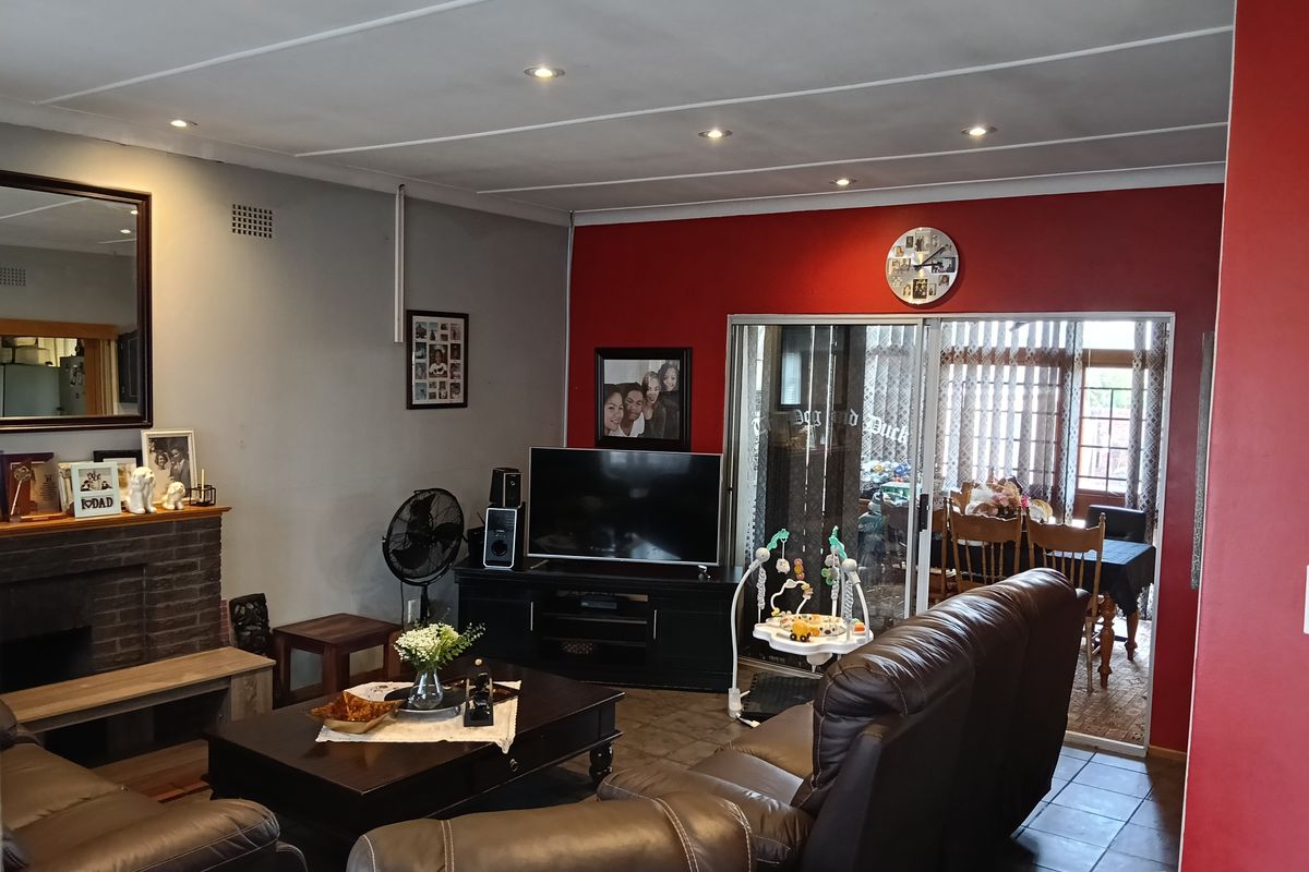 Spacious living room featuring a brick fireplace, tiled flooring, and sliding glass doors leading to an adjacent dining area.