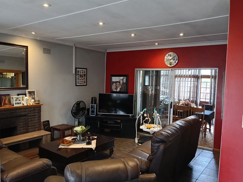 Spacious living room featuring a brick fireplace, tiled flooring, and sliding glass doors leading to an adjacent dining area.
