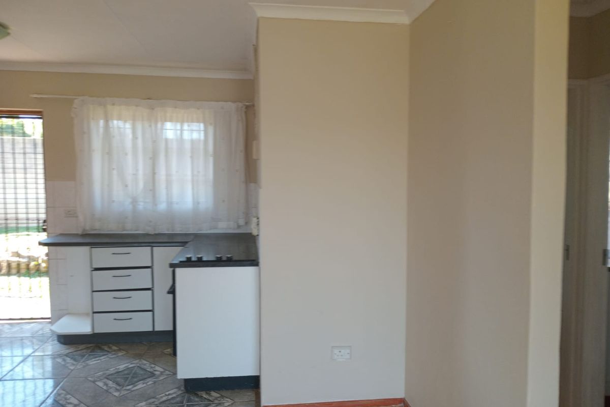 A functional kitchen area featuring built-in cabinetry, laminate countertops, and tiled flooring, offering a clean and neutral space ready for updates.