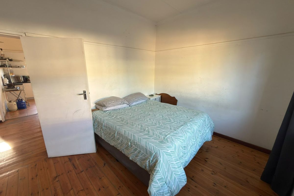 A bedroom featuring original timber flooring and a picture rail, requiring cosmetic updates to the wall finishes to improve the overall aesthetic.