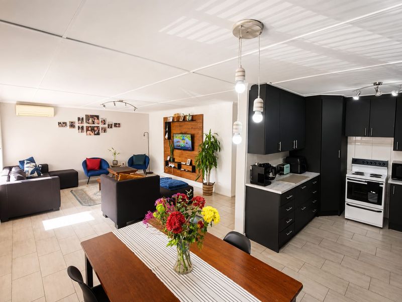 Spacious open-plan living area featuring a modern kitchen with dark cabinetry, tiled flooring, and integrated dining space, creating a functional and cohesive home layout.