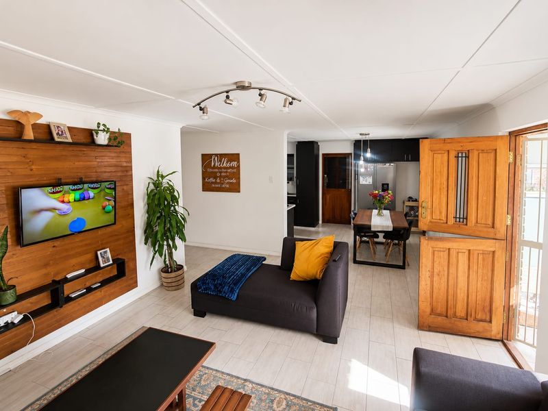 Open-plan living and dining area featuring a timber accent wall, tiled flooring, and a traditional stable-style entrance door leading to the exterior.