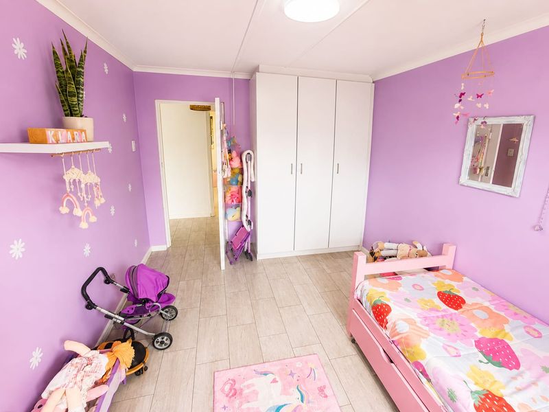 A bright bedroom featuring tiled flooring, a built-in wardrobe, and ample natural light, currently styled as a child's room.