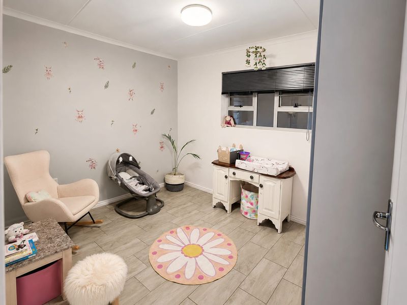 A well-maintained bedroom featuring neutral tiled flooring, a feature wall with decorative decals, and a window fitted with venetian blinds.