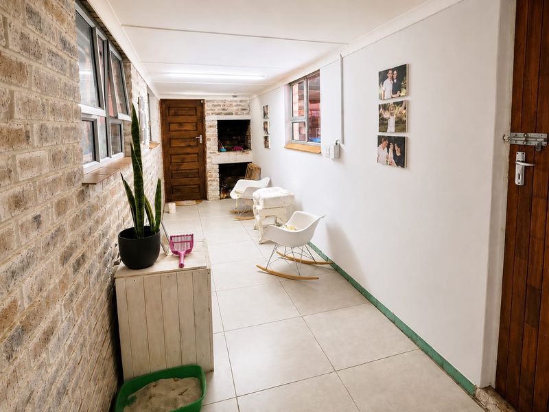 Enclosed patio area featuring a built-in braai, tiled flooring, and exposed brick wall detailing, offering a versatile space for indoor-outdoor entertaining.