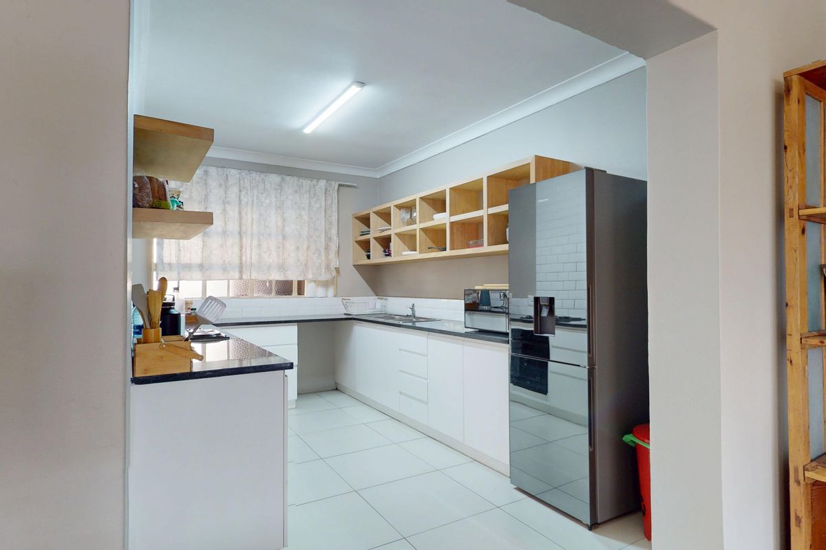 A functional kitchen featuring white cabinetry, open wooden shelving, subway tile backsplash, and tiled flooring, offering a clean and practical workspace.