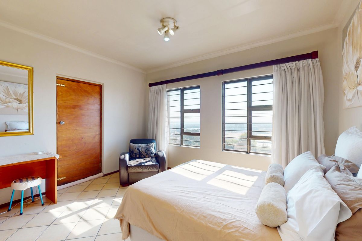 A bedroom featuring tiled flooring, security bars on the windows, and a built-in vanity unit.