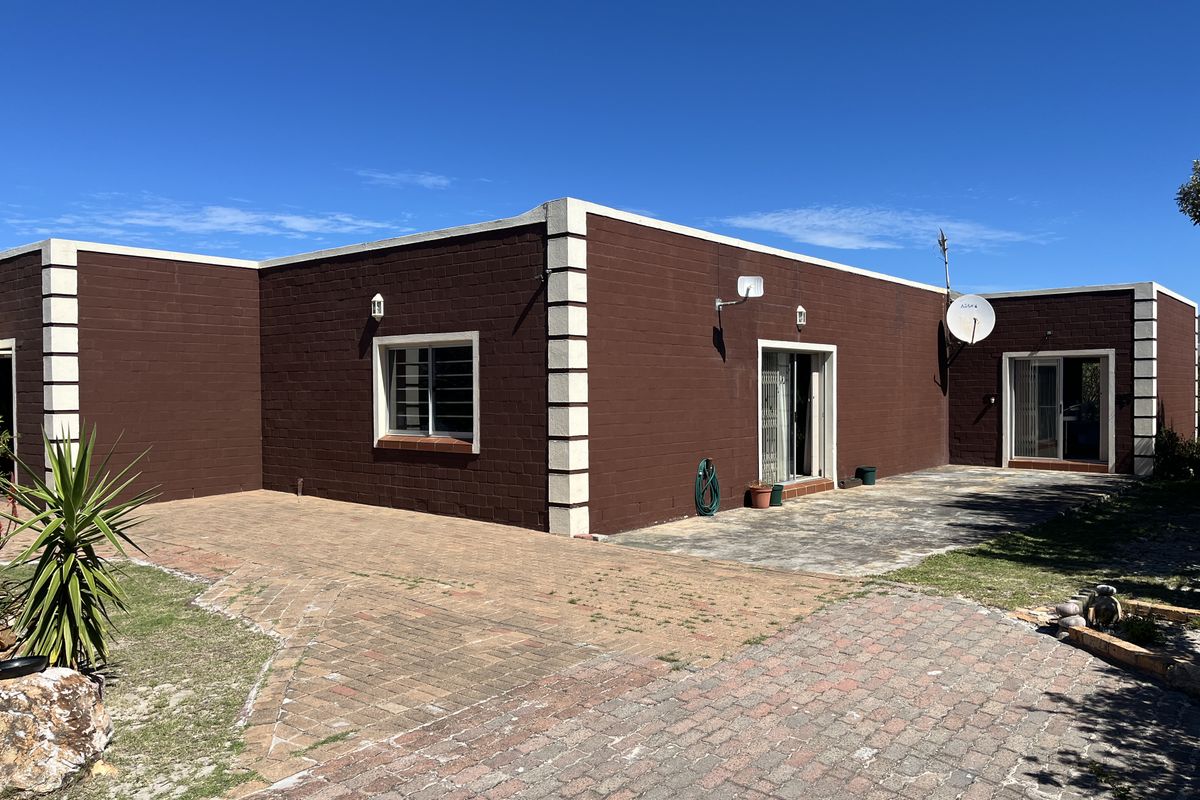 Rear exterior view of the house featuring a paved patio area, brick driveway, and sliding door access to the interior.