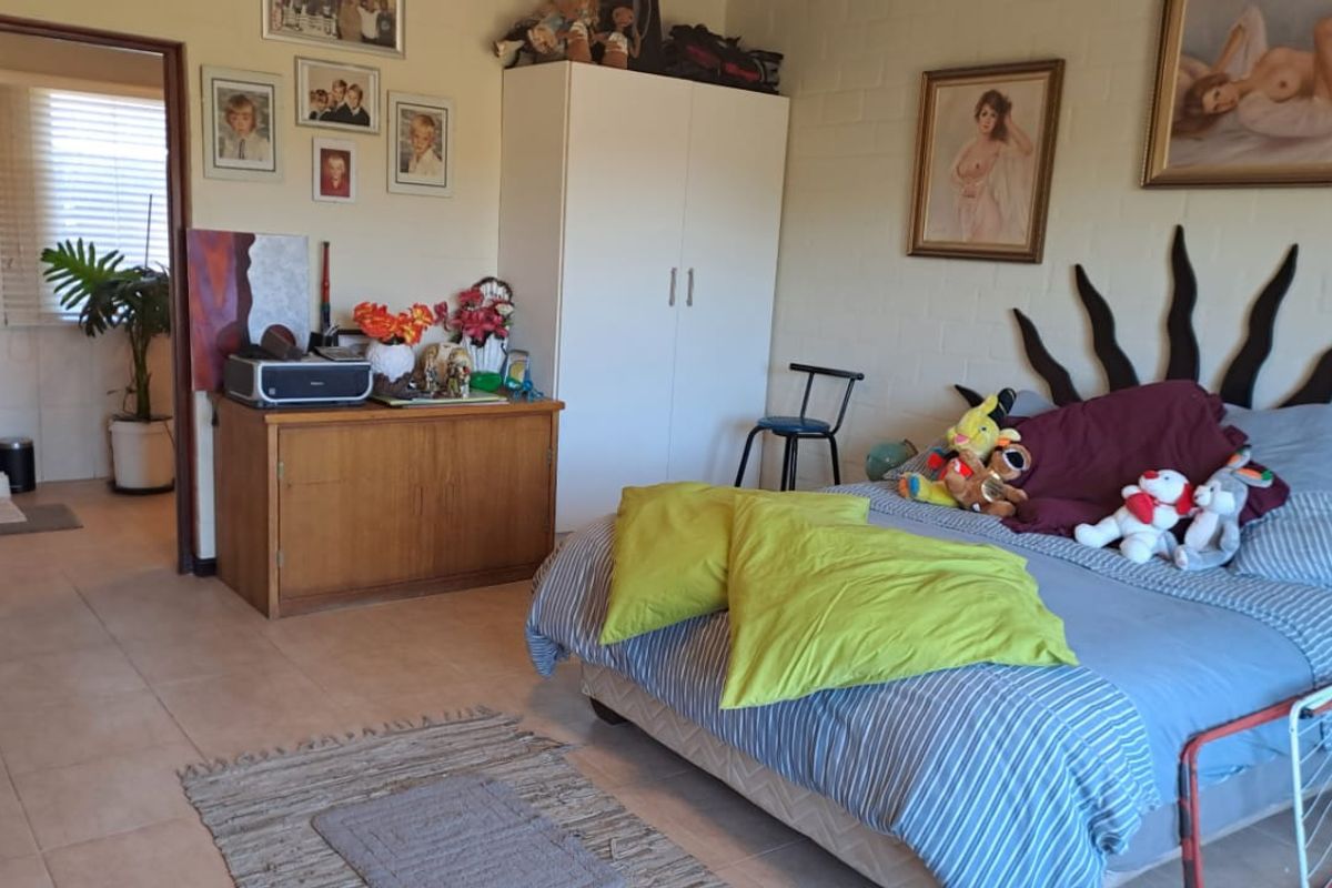 A bedroom featuring tiled flooring and painted brick walls, with an adjoining en-suite bathroom visible through the doorway.