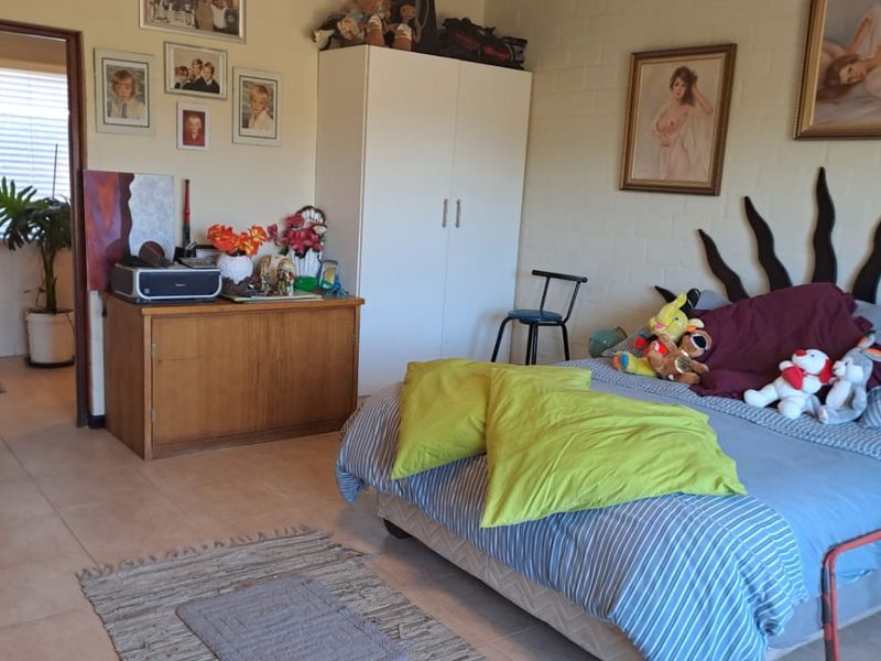 A bedroom featuring tiled flooring and painted brick walls, with an adjoining en-suite bathroom visible through the doorway.