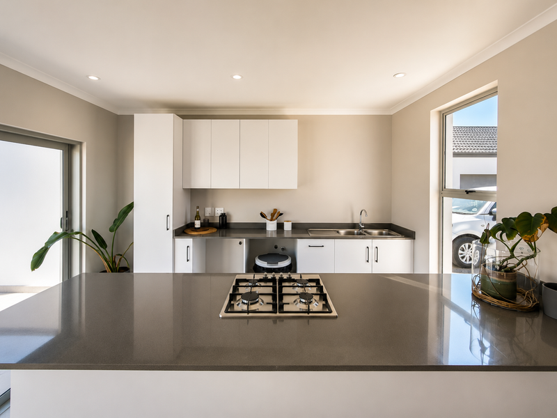 Modern kitchen featuring a central island with a gas hob, stone countertops, double sink, and clean white cabinetry.