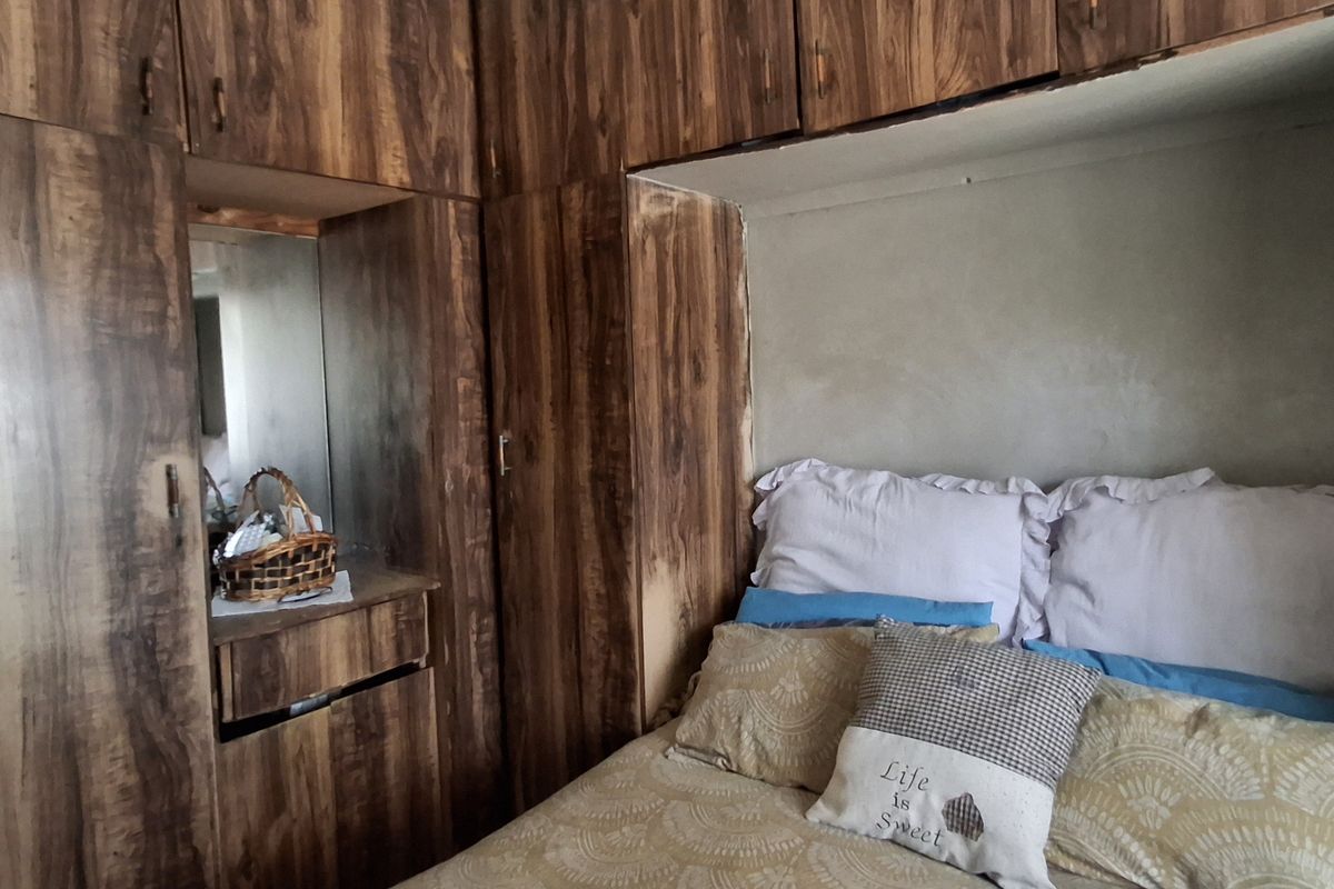 Bedroom featuring extensive built-in wooden cabinetry with an integrated vanity mirror and an unfinished wall section above the bed area.