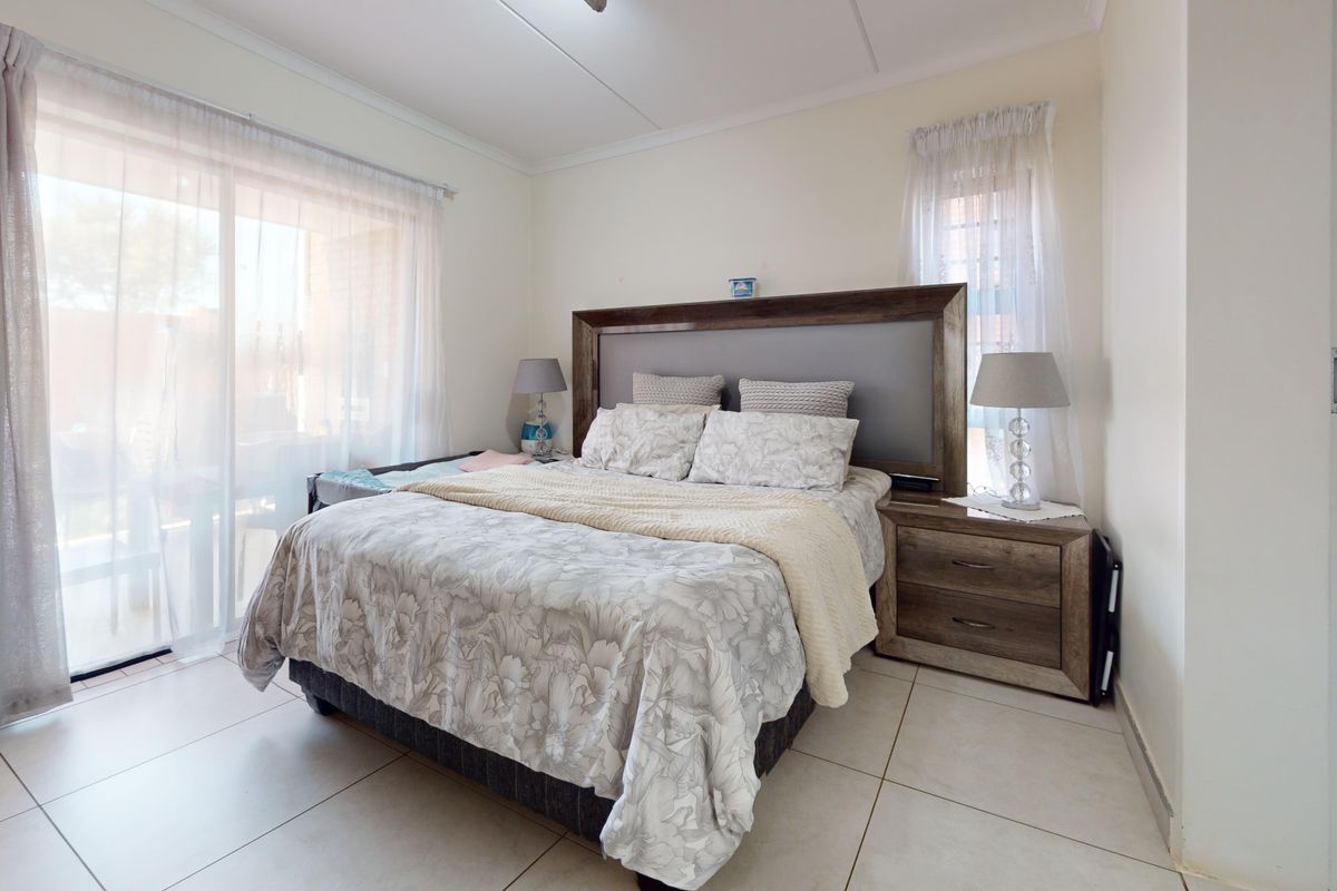 A well-lit bedroom featuring tiled flooring and a large sliding glass door providing access to an outdoor area.