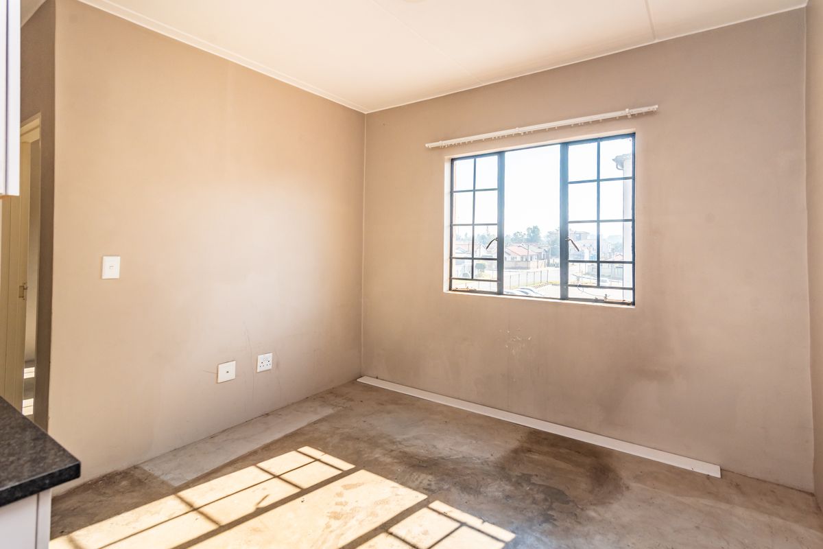 An empty bedroom featuring a steel-framed window, neutral wall paint, and concrete flooring, offering a blank canvas for renovation or interior design.